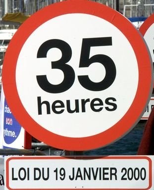 A MAN WALKS PAST SIGN POSTS READING 35 HOURS DURING DEMONSTRATION IN MARSEILLE.